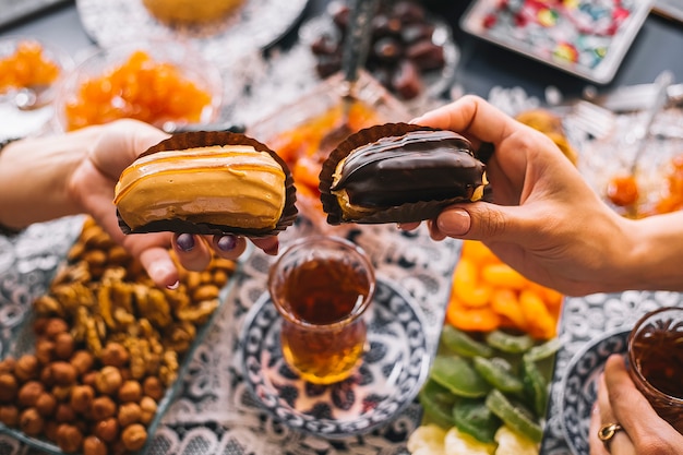 Two woman holding caramel and chocolate eclairs