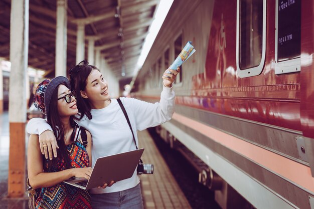 Two women are happy while traveling at the train station. Tourism concept