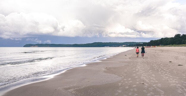 Two women are walking along an empty sea beach
