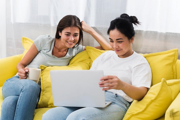 Две женщины дома, используя ноутбук на диване
