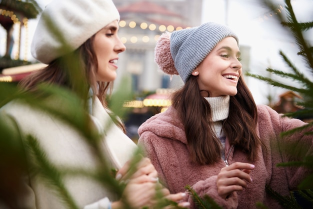 クリスマスマーケットでクリスマスツリーを選ぶ2人の女性