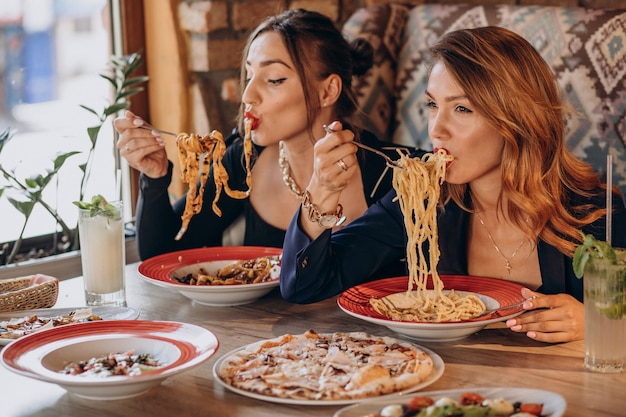Two women eating pasta in an italian restaurant
