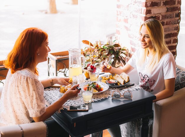 Two women having lunch together sitting near the window at cafe