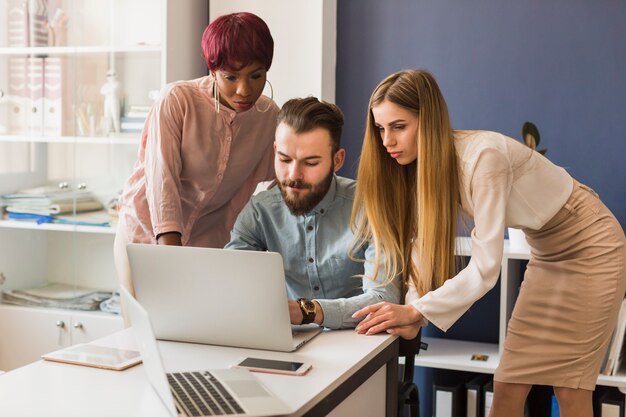 Two women helping man with project