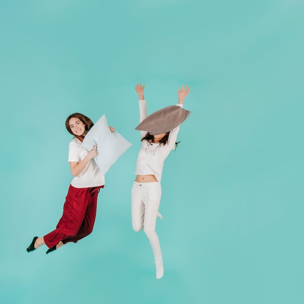 Бесплатное фото Две женщины, прыгающие с подушками