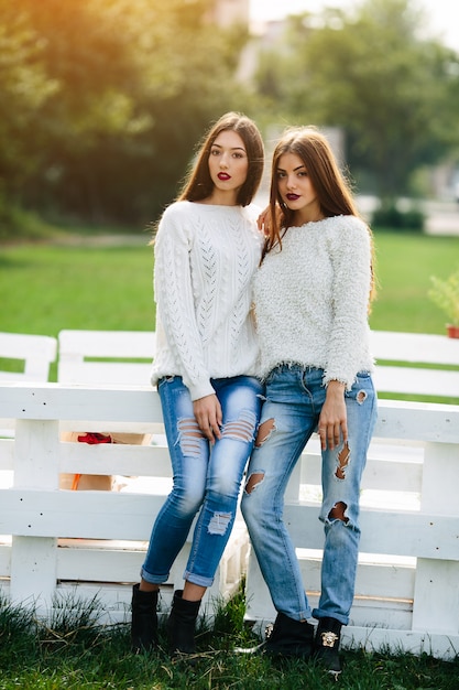 Free photo two women lean on a white bench in the park