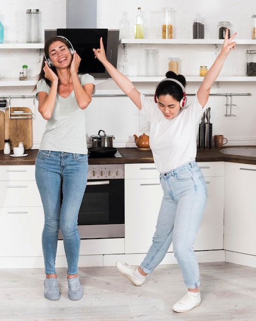 Free photo two women listening and dancing to music on headphones