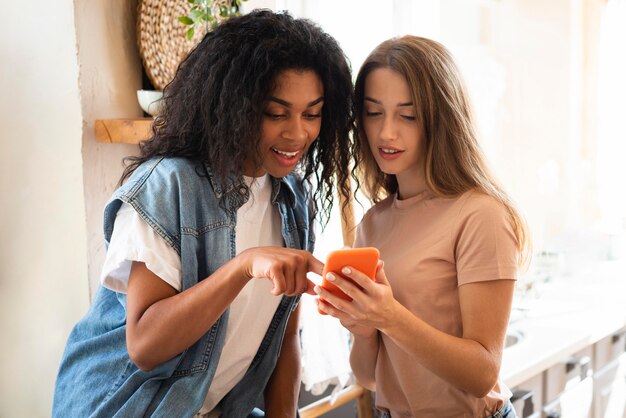 Two women looking together on smartphone at home