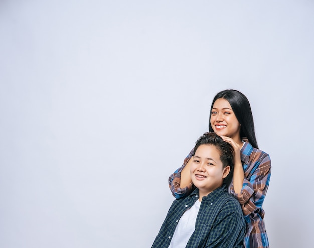 Two women in love stand and place their hands on each other's heads.