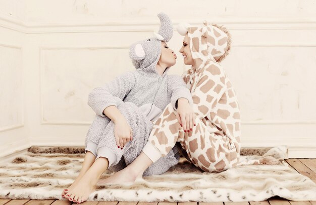 Two women in pajamas kissing each other.