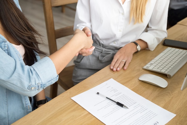 Two women partners handshaking after signing business contract at meeting