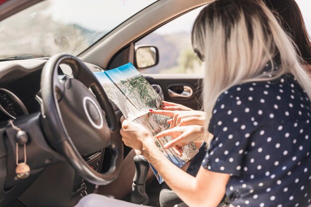 Two women sitting in car pointing on map