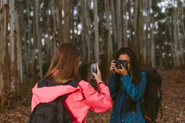 Two women taking photograph of each other with camera and cellphone