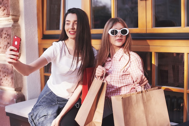 Two women talking after shopping on the street near the window.