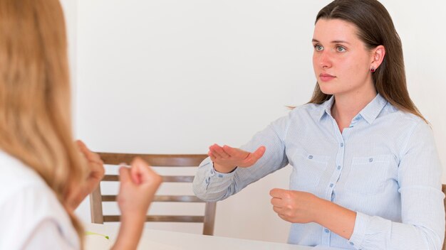 Two women using sign language to communicate at table