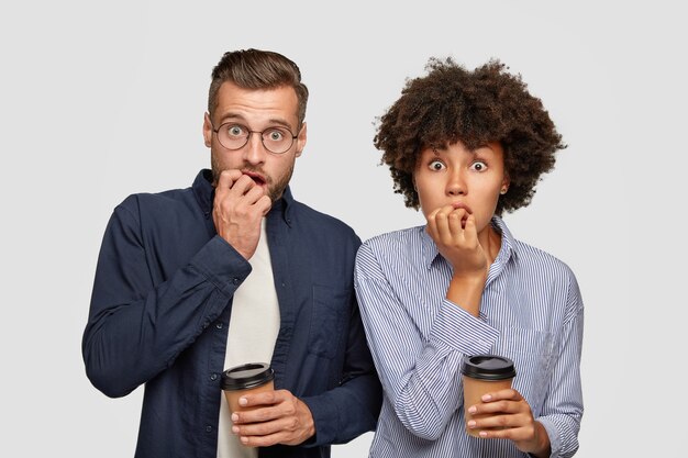 Two worried mixed race students bite finger nails, wait for results