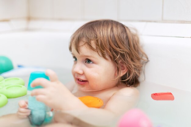 two-year kid bathes with toys