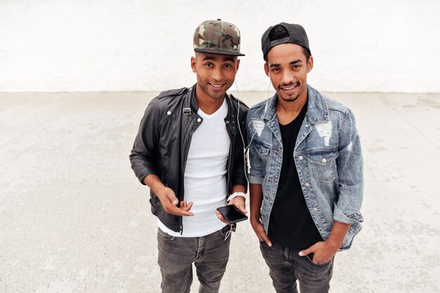 Two young african men friends walking outdoors listening music.