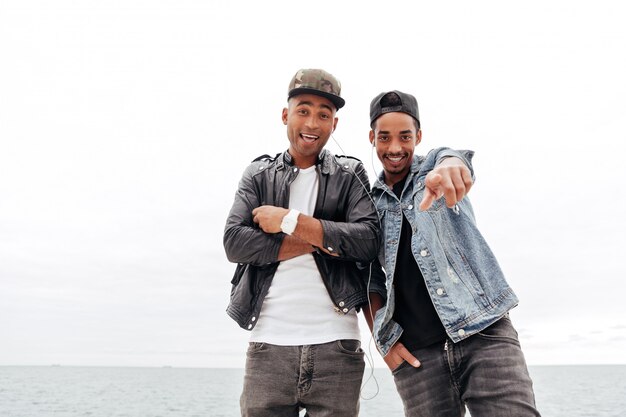 Two young african men friends walking outdoors listening music.