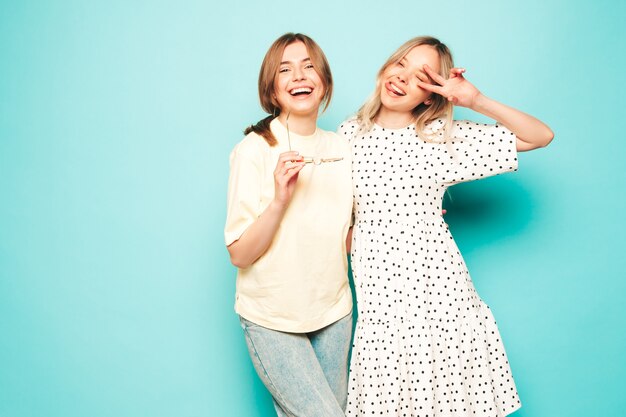 Two young beautiful blond smiling hipster female in trendy summer clothes