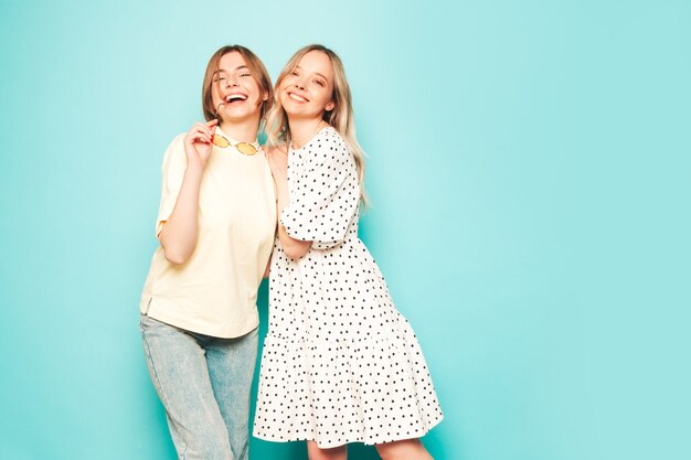 Two young beautiful blond smiling hipster female in trendy summer clothes