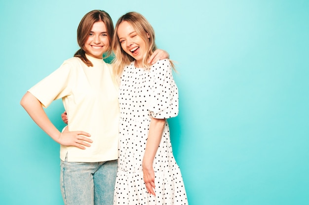 Two young beautiful blond smiling hipster female in trendy summer clothes