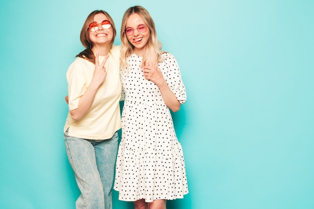 Two young beautiful blond smiling hipster female in trendy summer clothes