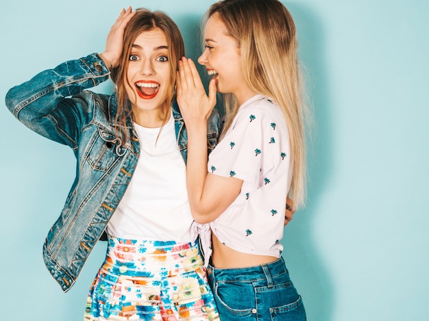 Two young beautiful blond smiling hipster girls in trendy summer casual clothes. 