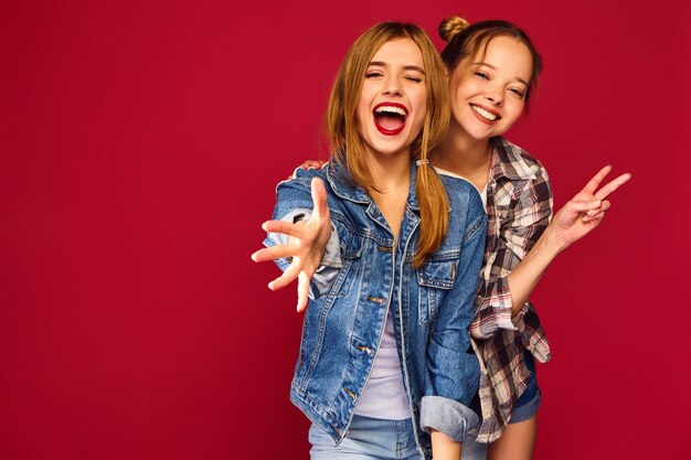 Two young beautiful blond smiling hipster women posing in trendy summer checkered shirt clothes