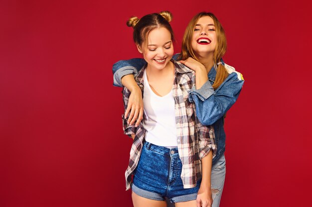 Two young beautiful blond smiling hipster women posing in trendy summer checkered shirt clothes