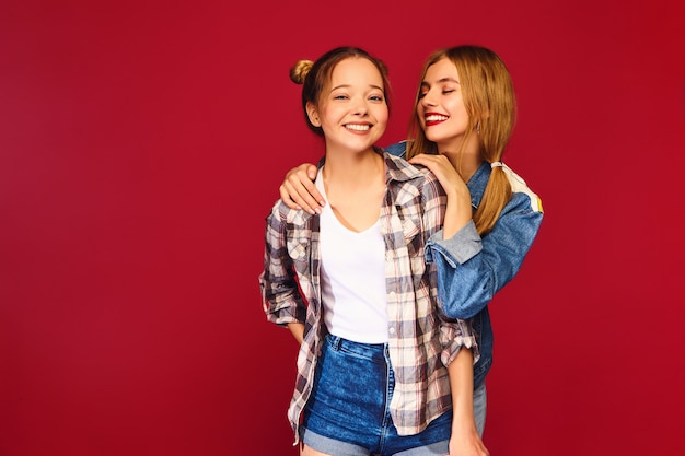 Two young beautiful blond smiling hipster women posing in trendy summer checkered shirt clothes