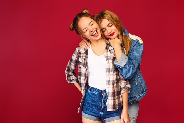 Two young beautiful blond smiling hipster women posing in trendy summer checkered shirt clothes