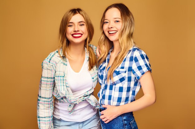 Две молодые красивые блондинки улыбаются в модные летние клетчатые рубашки