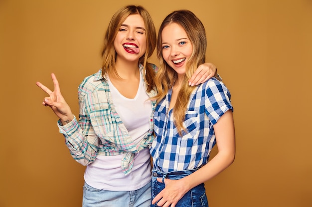 Two young beautiful blond smiling in trendy summer checkered shirts