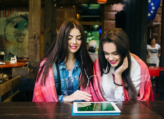 タブレットで何かを見ているテーブルに座っている2人の若くて美しい少女