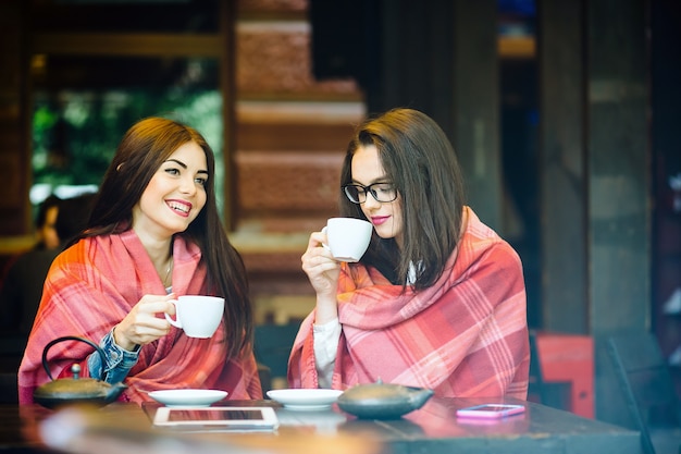 Due ragazze giovani e belle che spettegolano sulla terrazza con una tazza di caffè