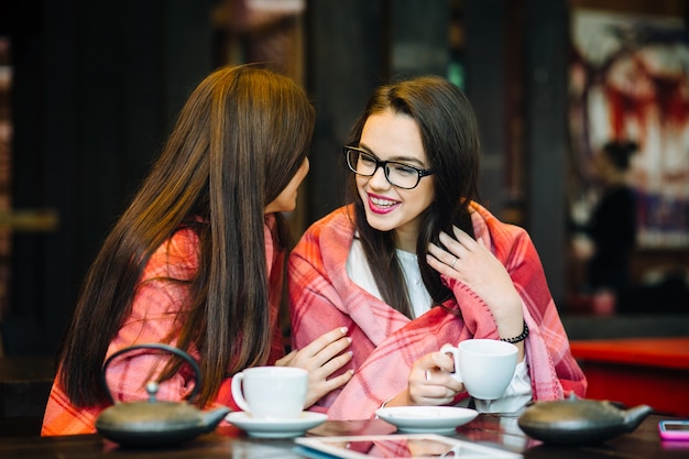 一杯のコーヒーとテラスでおしゃべりする2人の若くて美しい女の子