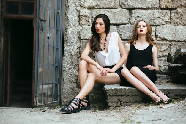 Two young beautiful girls posing against of an abandoned building