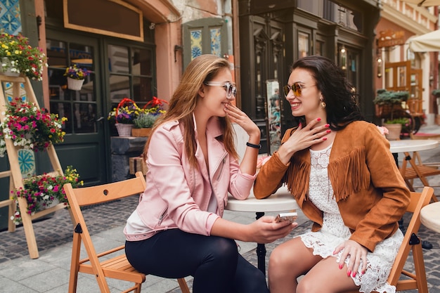 Two young beautiful hipster women sitting at cafe