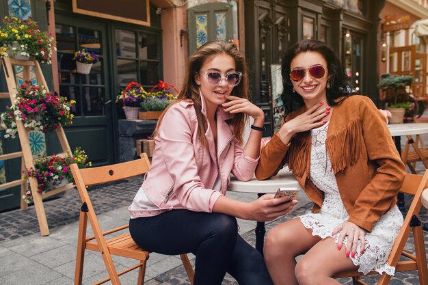 Two young beautiful hipster women sitting at cafe