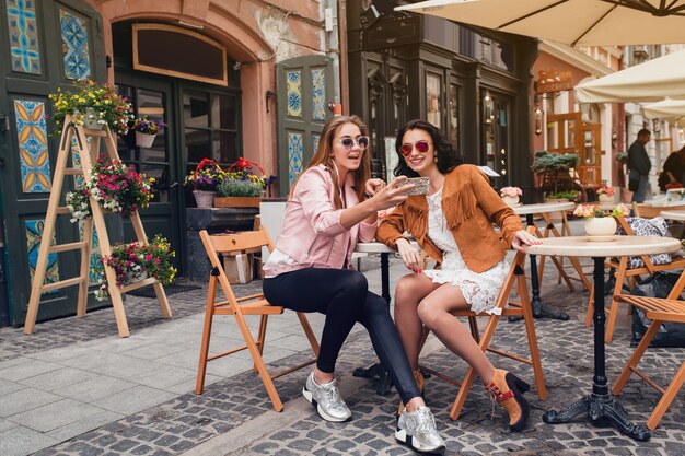 Two young beautiful hipster women sitting at cafe