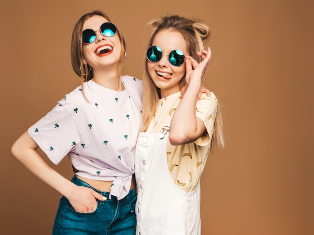 トレンディな夏のカラフルなtシャツの服の2人の若い美しい笑顔金髪流行に敏感な女の子。