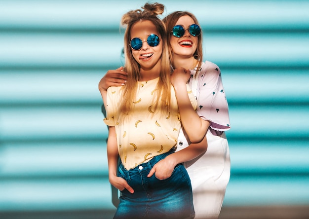 Free photo two young beautiful smiling blond hipster girls in trendy summer colorful t-shirt clothes.