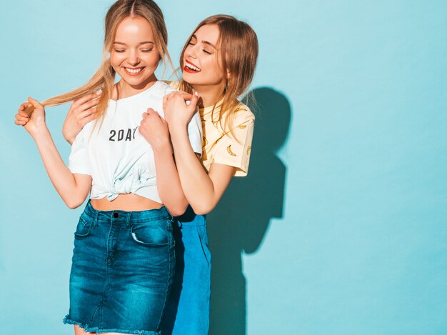 Two young beautiful smiling blond hipster girls in trendy summer colorful T-shirt clothes. 