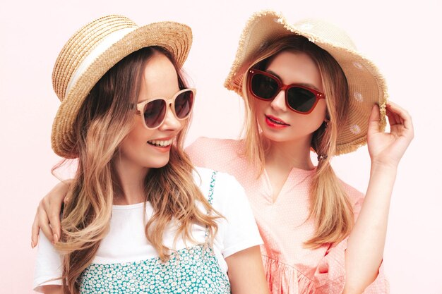 Two young beautiful smiling brunette hipster female in trendy summer dresses Sexy carefree women posing near pink wall Positive models having fun Cheerful and happy