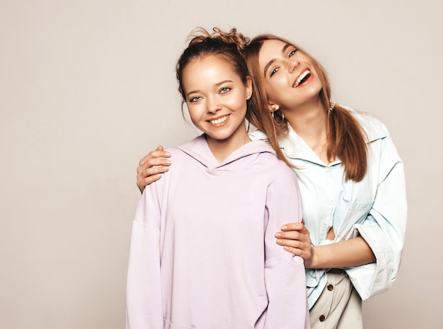 Two young beautiful smiling girls in trendy summer clothes. Sexy carefree women. Positive models