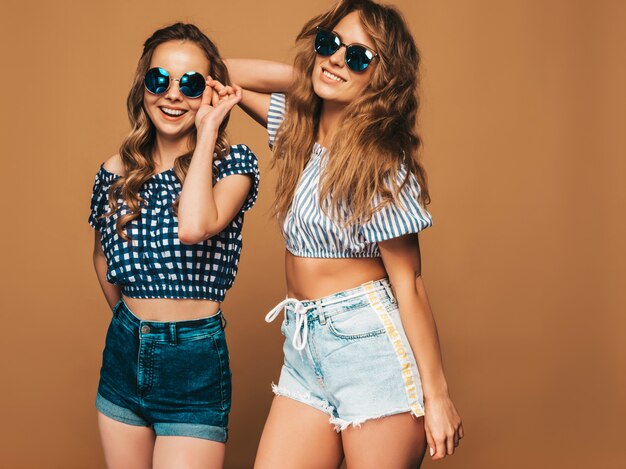 Two young beautiful smiling girls in trendy summer clothes and sunglasses. Sexy carefree women posing. Positive models