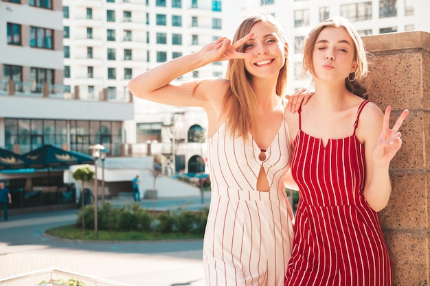 Free photo two young beautiful smiling hipster female in trendy overallssexy carefree women posing on the street background positive models having fun hugging and going crazy