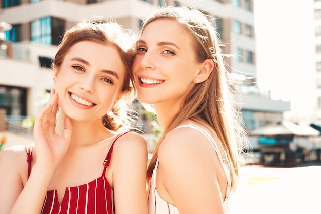 Two young beautiful smiling hipster female in trendy overallsSexy carefree women posing on the street background Positive models having fun hugging and going crazyBeauty concept