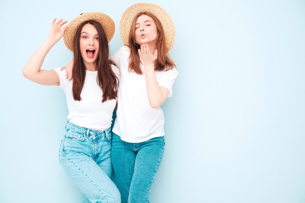 Two young beautiful smiling hipster female in trendy same summer white t-shirt and jeans clothes